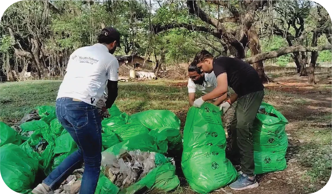 Volunteer carrying a filled garbage bag in a park during cleanup